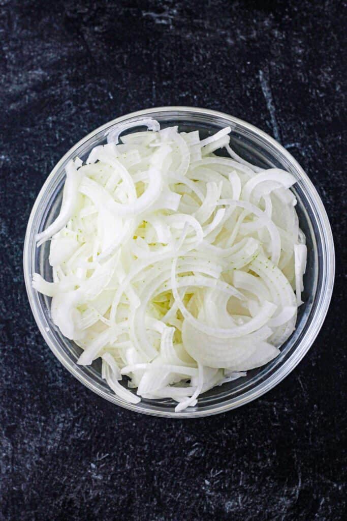Sliced raw onions in a glass bowl.
