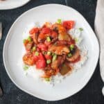 Vegan Pepper Steak with mushrooms and onions served over rice and garnished with sliced green onions.