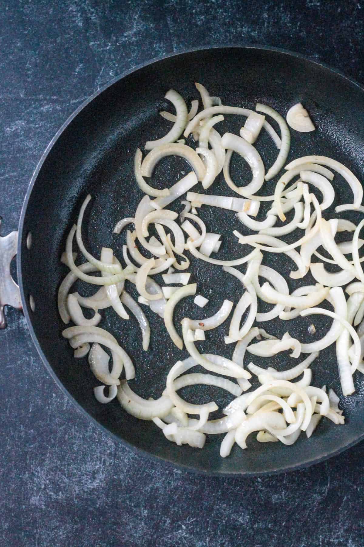 Sautéed sliced onions in a skillet.