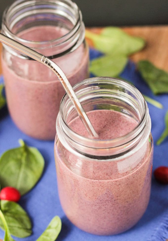 Purplish pink Coconut Water Smoothie with a metal straw in front of another coconut water smoothie with no straw.