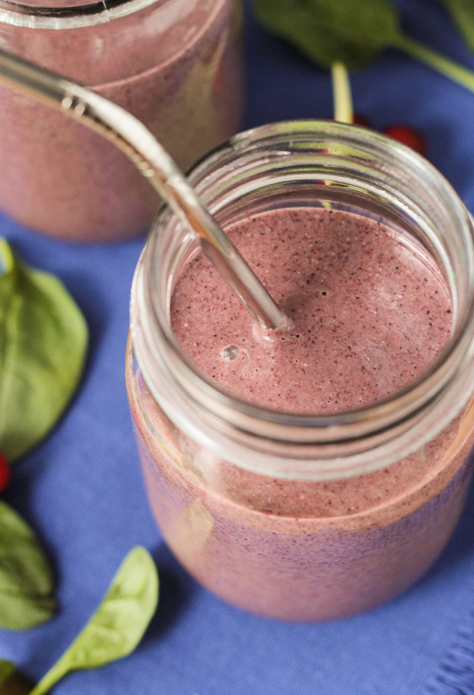 A purplish pink Coconut Water Smoothie in a glass jar with a metal straw.