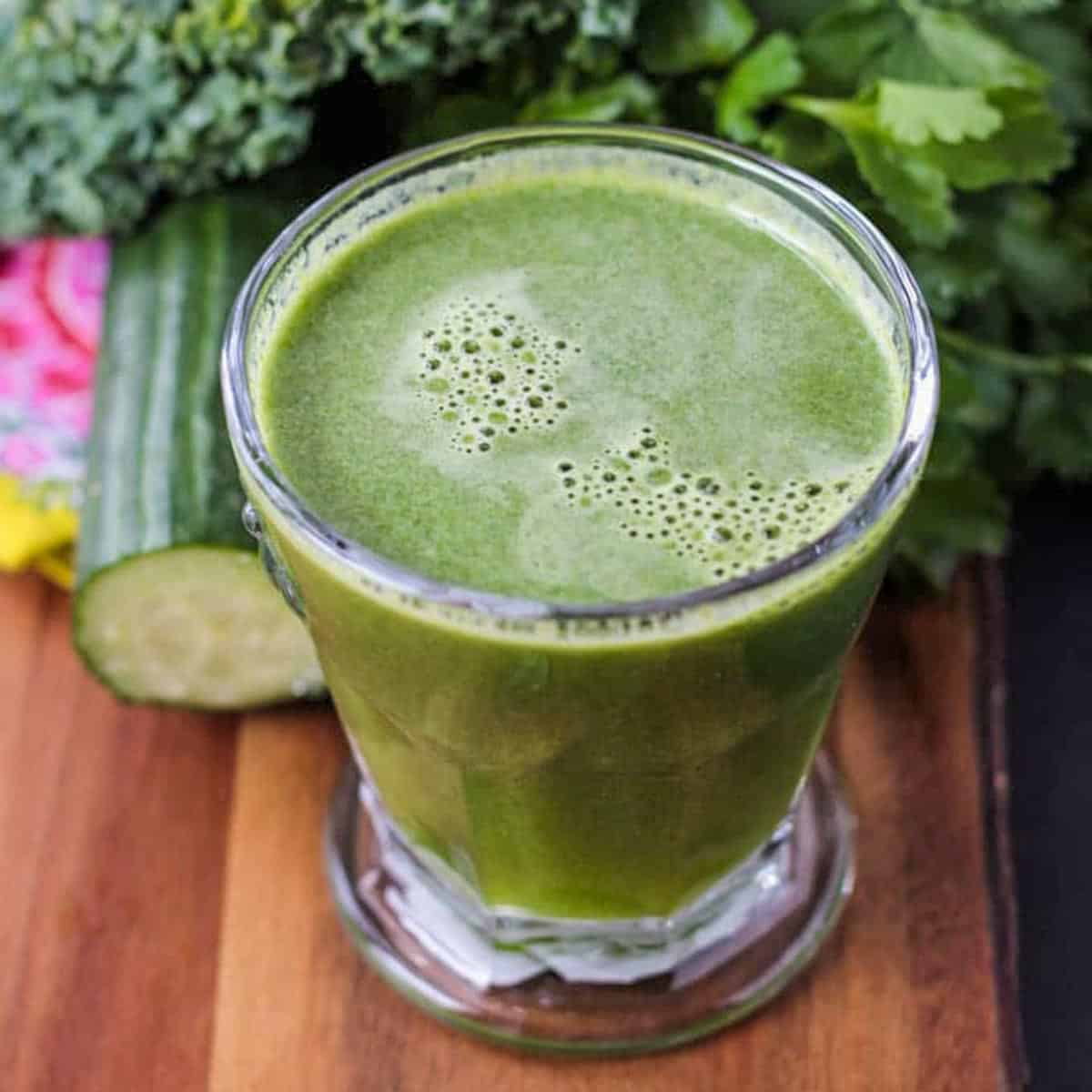 Glass of green juice surrounded by fresh produce.