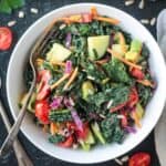 Chopped kale salad with a variety of vegetables in a white bowl.