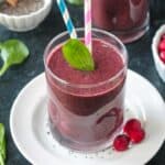One fresh spinach leaf and two straws in a coconut water smoothie.