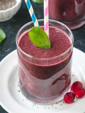 One fresh spinach leaf and two straws in a coconut water smoothie.