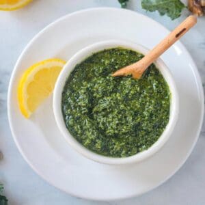 Small wooden spoon in a bowl of kale walnut pesto.