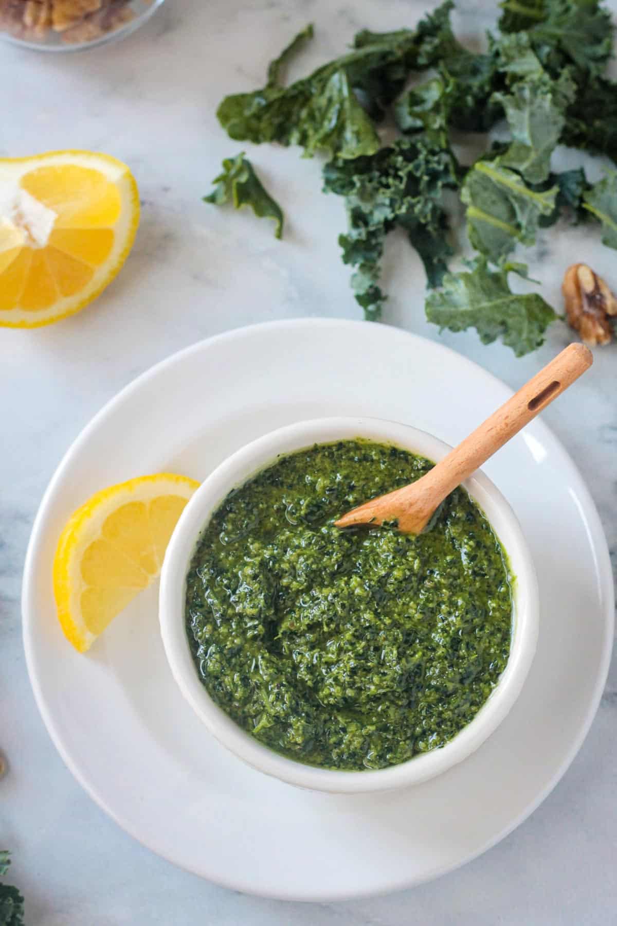 Small wooden spoon in a bowl of kale walnut pesto.