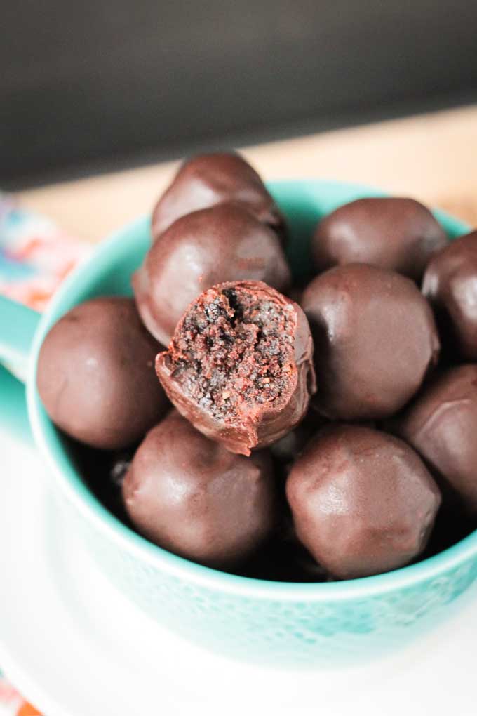Bowl of Cherry Chocolate Dairy Free Truffles. Top truffle has a bite taken out showing the fudgy inside.