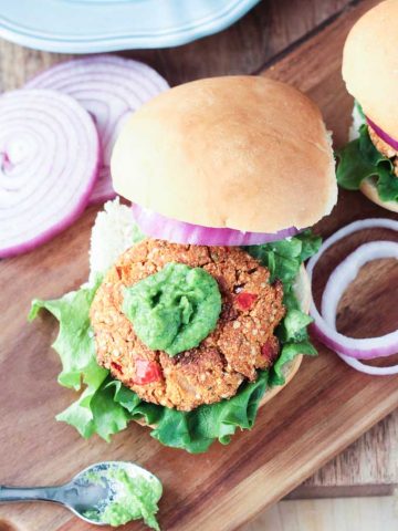 Tofu Hemp veggie burger topped with red onion slices, lettuce, and herbed bean spread.