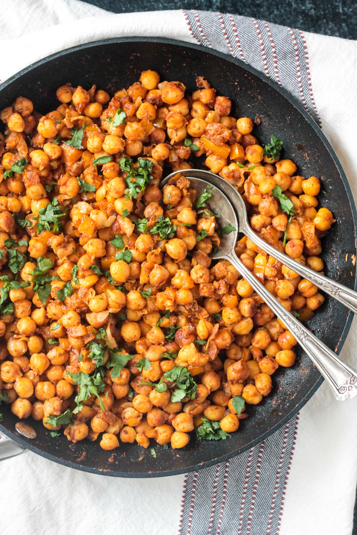 Close up of seasoned chickpeas on a spoon in a skillet.