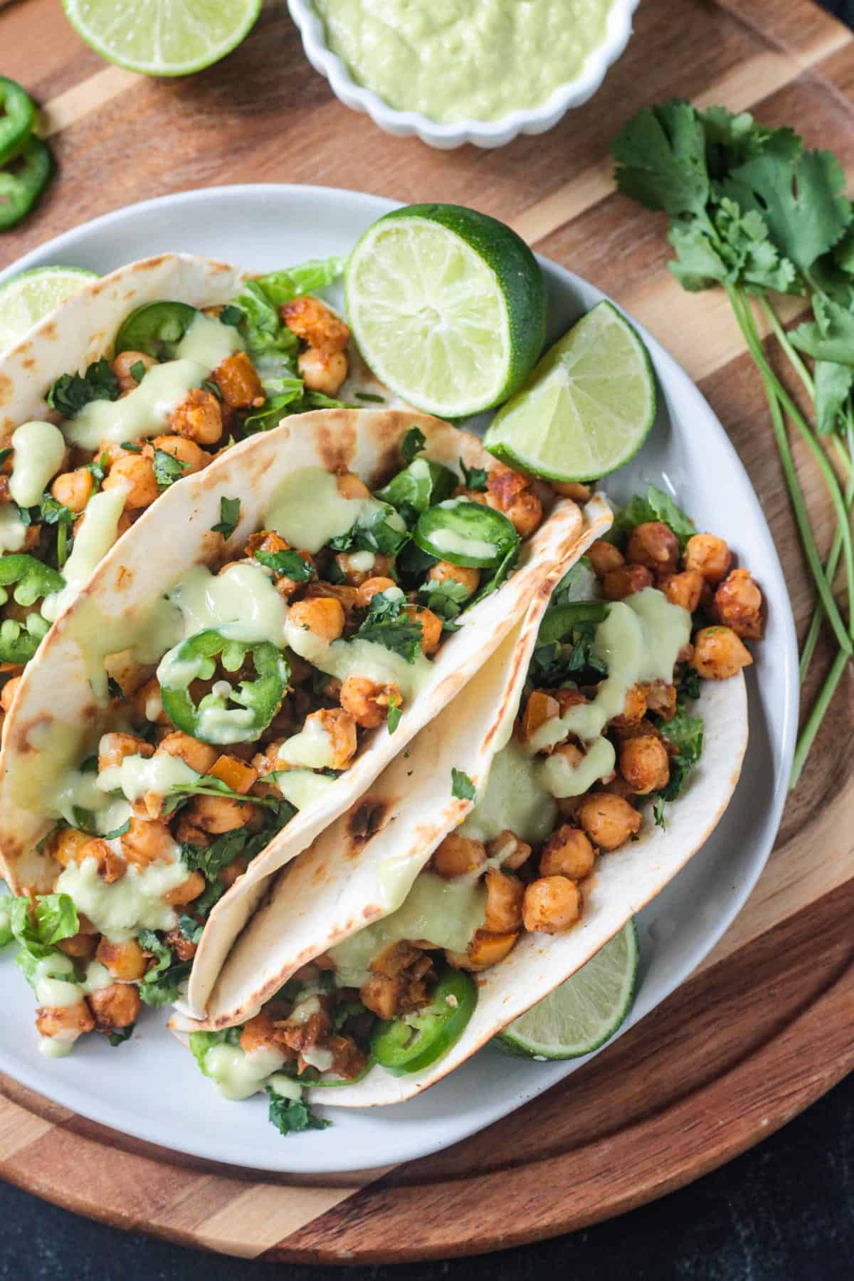 Chickpea and peppers in tacos toped with jalapeño slices and avocado sauce.