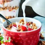 Milk being poured from a white pitcher into a breakfast bowl.