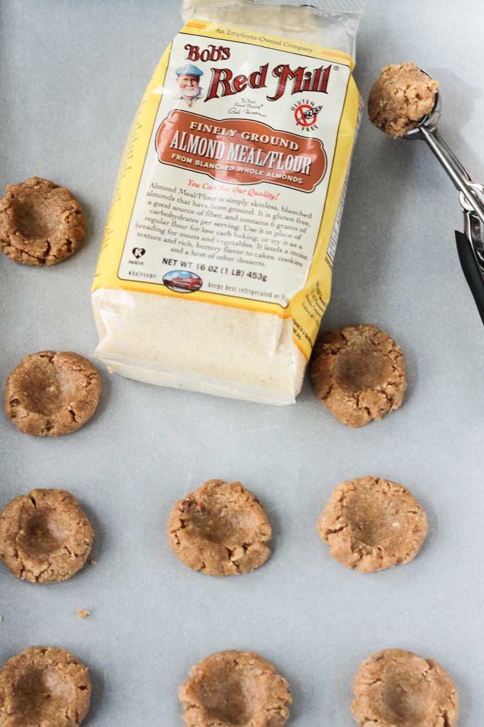 Raw Gluten Free Thumbprint Cookie dough on a piece of parchment paper with a bag of Bob's Red Mill Almond Flour