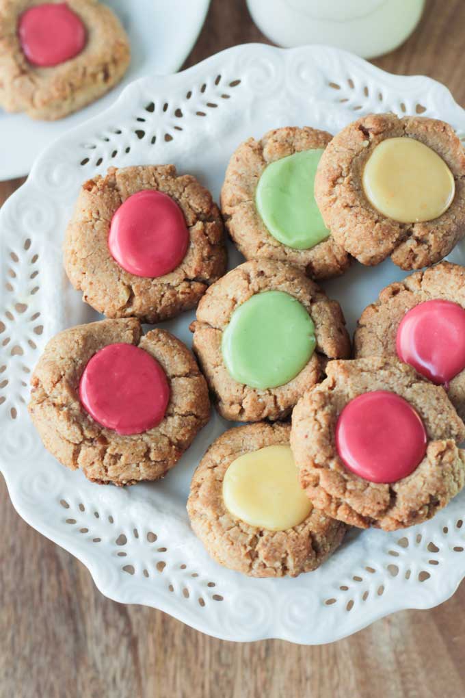 A pile of pastel iced Gluten Free Thumbprint Cookies on a white plate.