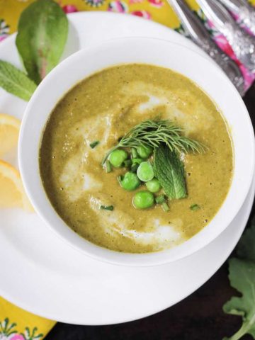 Creamy green vegetable soup topped with green peas, fresh dill, & mint leaf.