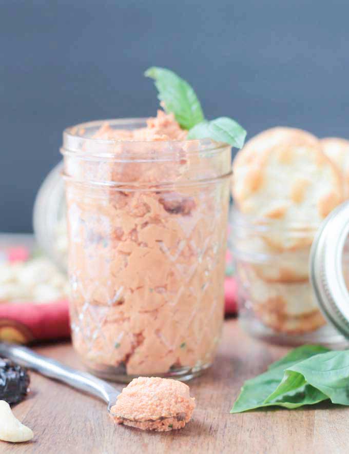 Front view of a jar of Sun Dried Tomato Spread. Small jar of crackers behind.