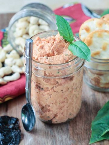 Sun Dried Tomato Spread in a glass jar with a sprig of basil on top