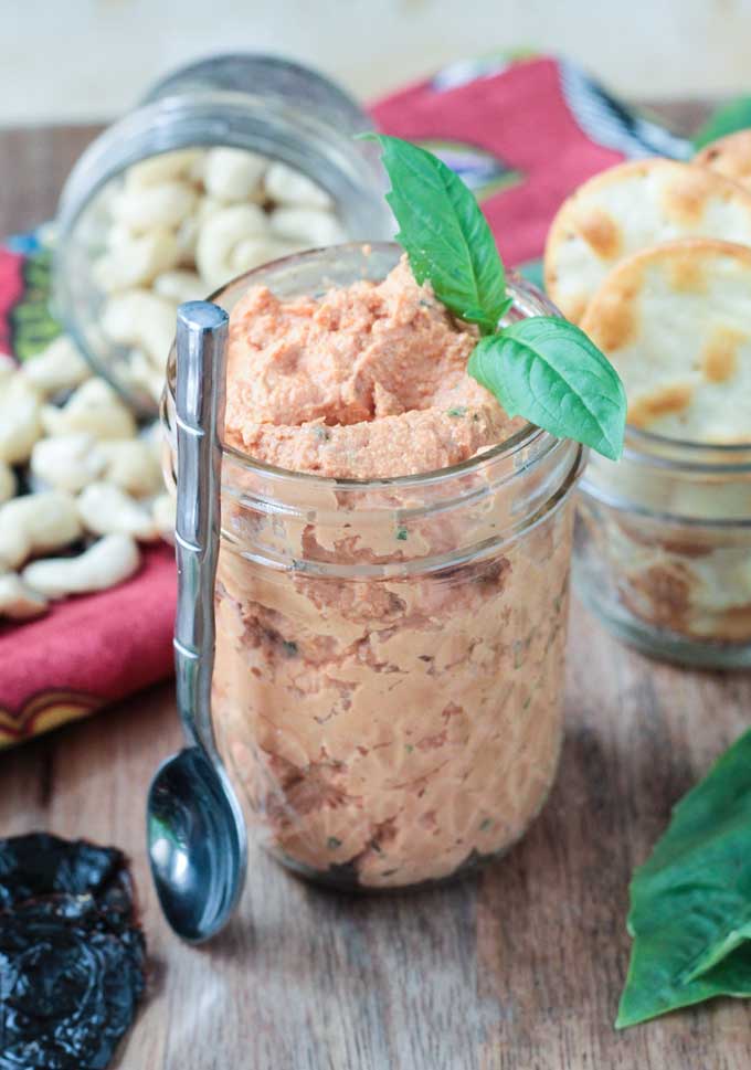 Sun Dried Tomato Spread in a glass jar with a sprig of basil on top