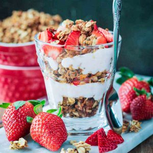 Coconut Chia Granola layered with dairy free yogurt and fresh strawberries in a parfait glass.