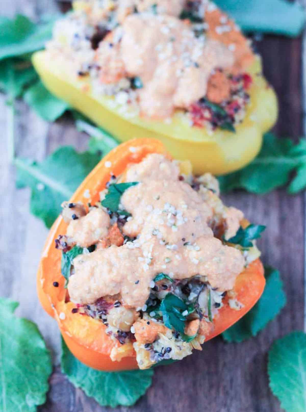 Close up of a halved orange bell pepper stuffed with quinoa and topped with sauce.