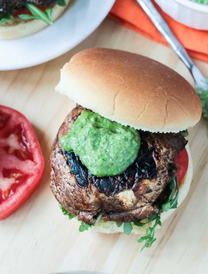 A grilled portobello mushroom topped with pesto on a burger bun.