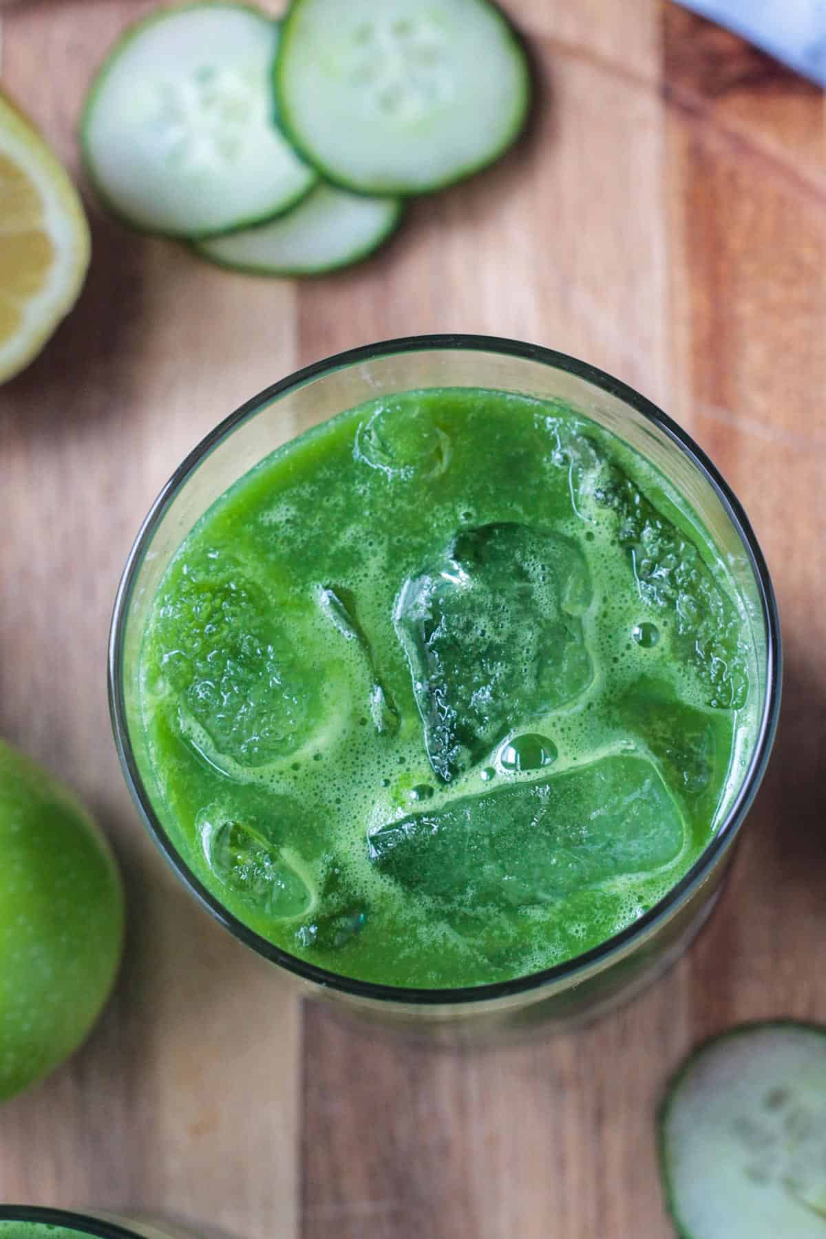 Overhead view of a glass of green blender juice with ice.