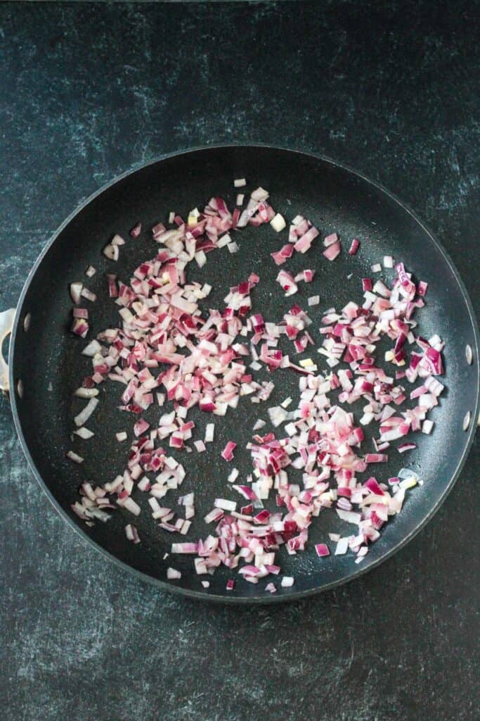 Sautéed diced red onions in a large skillet.