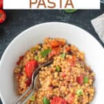 Tomato basil pasta fregola in a bowl with two forks.
