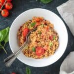 Tomato basil pasta fregola in a bowl with two forks.
