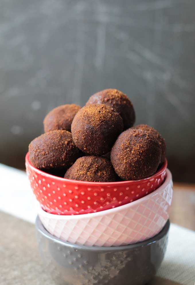 Three stacked bowls - one red, one pink, one gray. In the red bowl on top, a pile of Cinnamon Chickpea Dairy Free Truffles