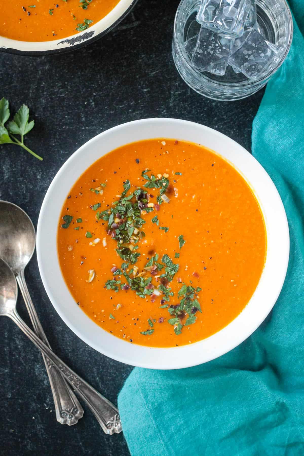 Creamy Carrot Soup topped with chopped parsley and red pepper flakes.