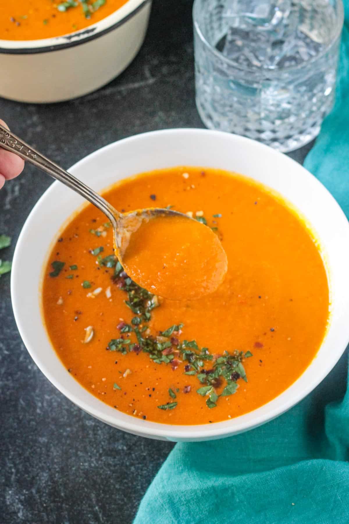 Spoonful of carrot soup being lifted out of a bowl.