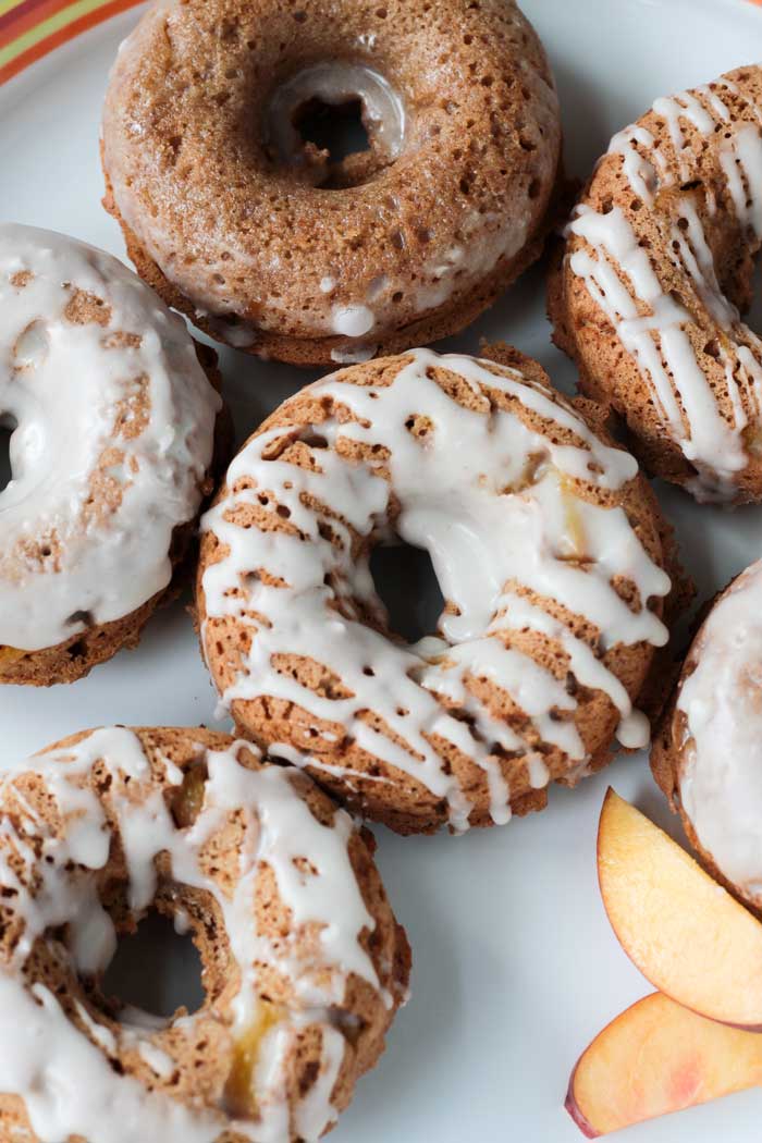 Plate of Peaches and Cream Dairy Free Donuts. Some drizzled with icing, some fully coated in icing.