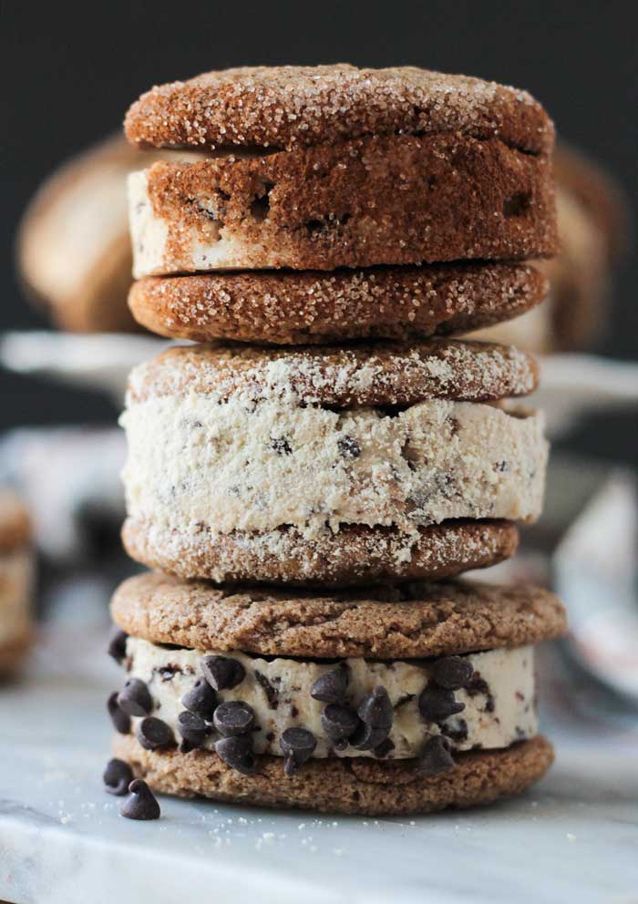 Stack of 3 ice cream cookie sandwiches. Top one rolled in cinnamon sugar, middle one rolled in powdered cashews, bottom rolled in mini chocolate chips.
