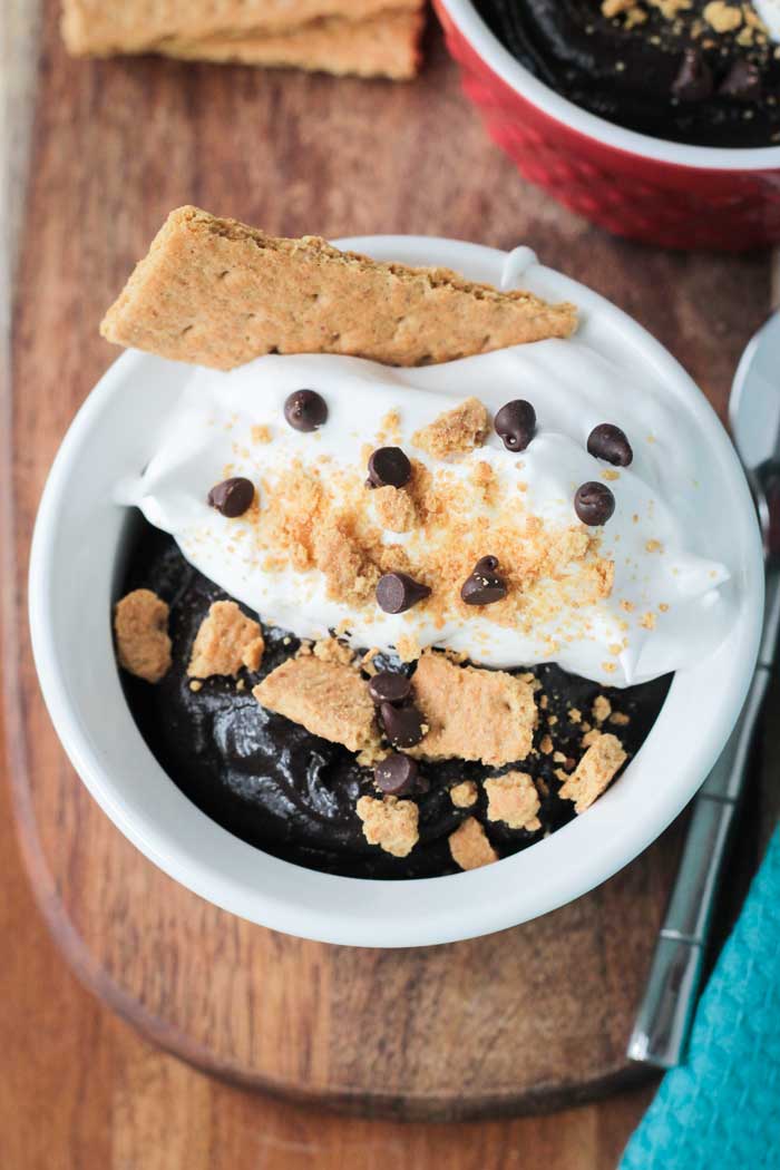Overhead view of a bowl of s'more chocolate pudding, whipped cream, graham cracker crumbs, and mini chocolate chips.