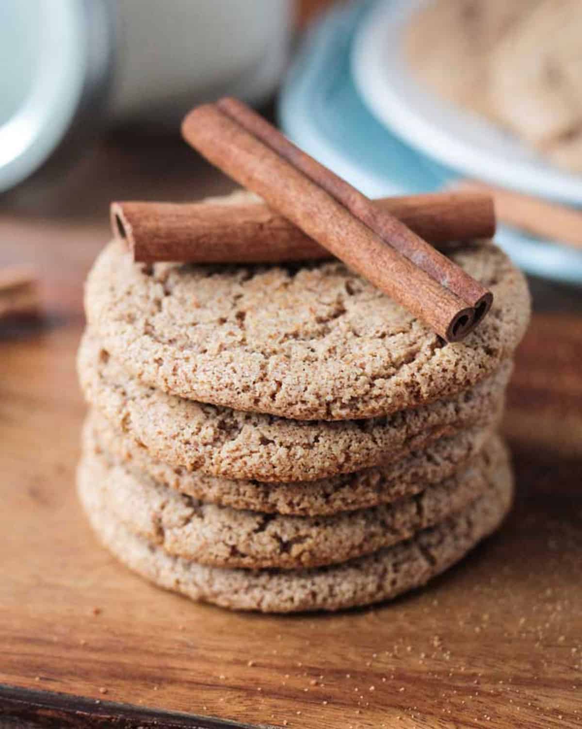Cinnamon Sugar Cookies - perfectly crispy on the outside, chewy on the inside, sweet, delicious, and packed with warm cinnamon. Only 6 ingredients and 15 minutes needed to make these quick and easy, gluten free cookies! They're going to become your go-to sweet treat! Two cinnamon sticks on top of a stack of cookies.