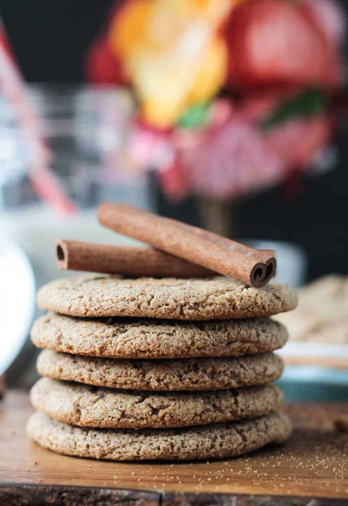 Stack of 5 thin cinnamon cookie with two cinnamon sticks on top.