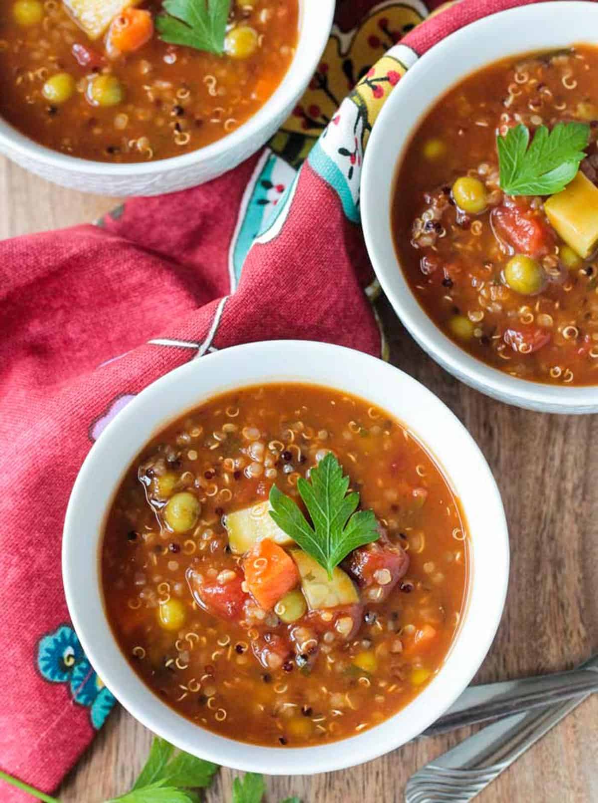 Three bowls of quinoa vegetable soup on a table.