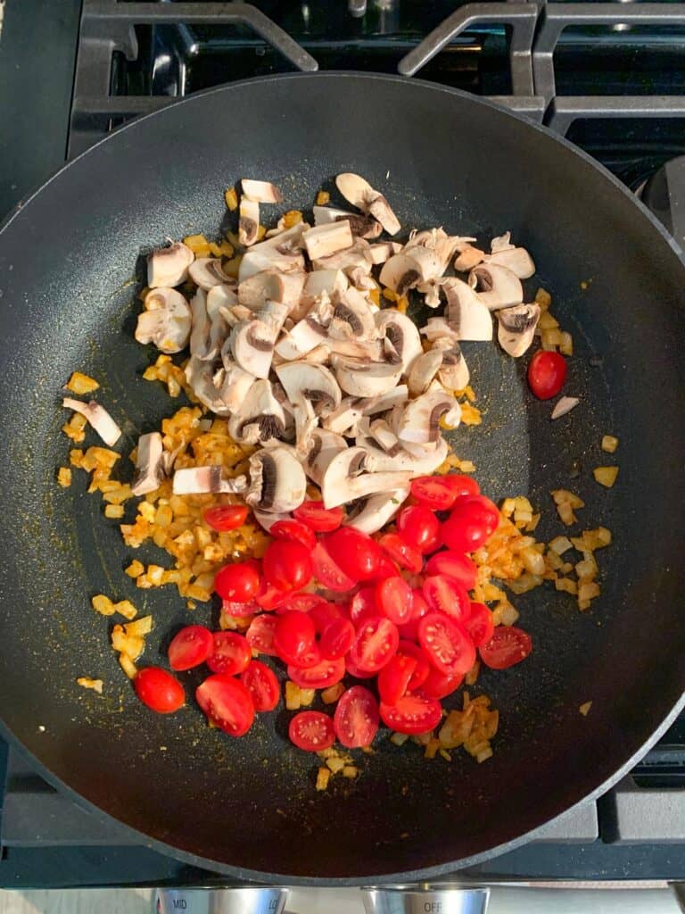 Tomatoes, mushrooms, and onions in a skillet.