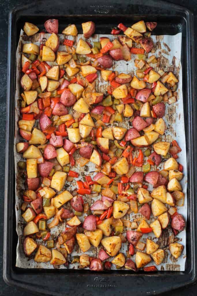 Roasted diced potatoes and peppers on a sheet pan.