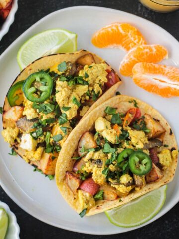 Two vegan breakfast tacos filled with tofu scramble and roasted potatoes.