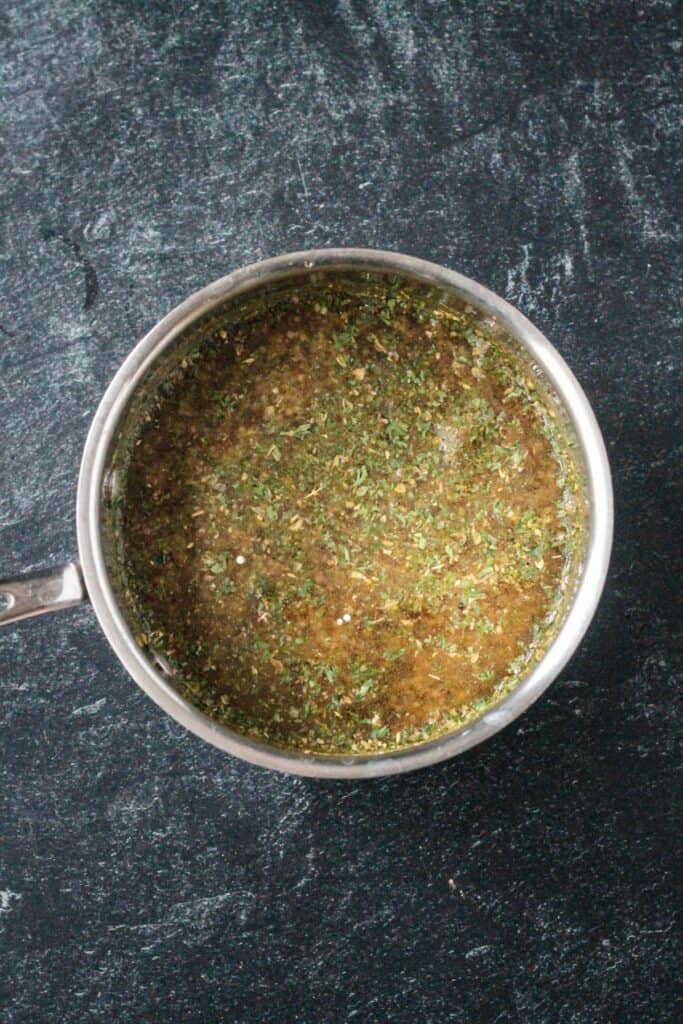 Dry quinoa in a pot with water and dried herbs.