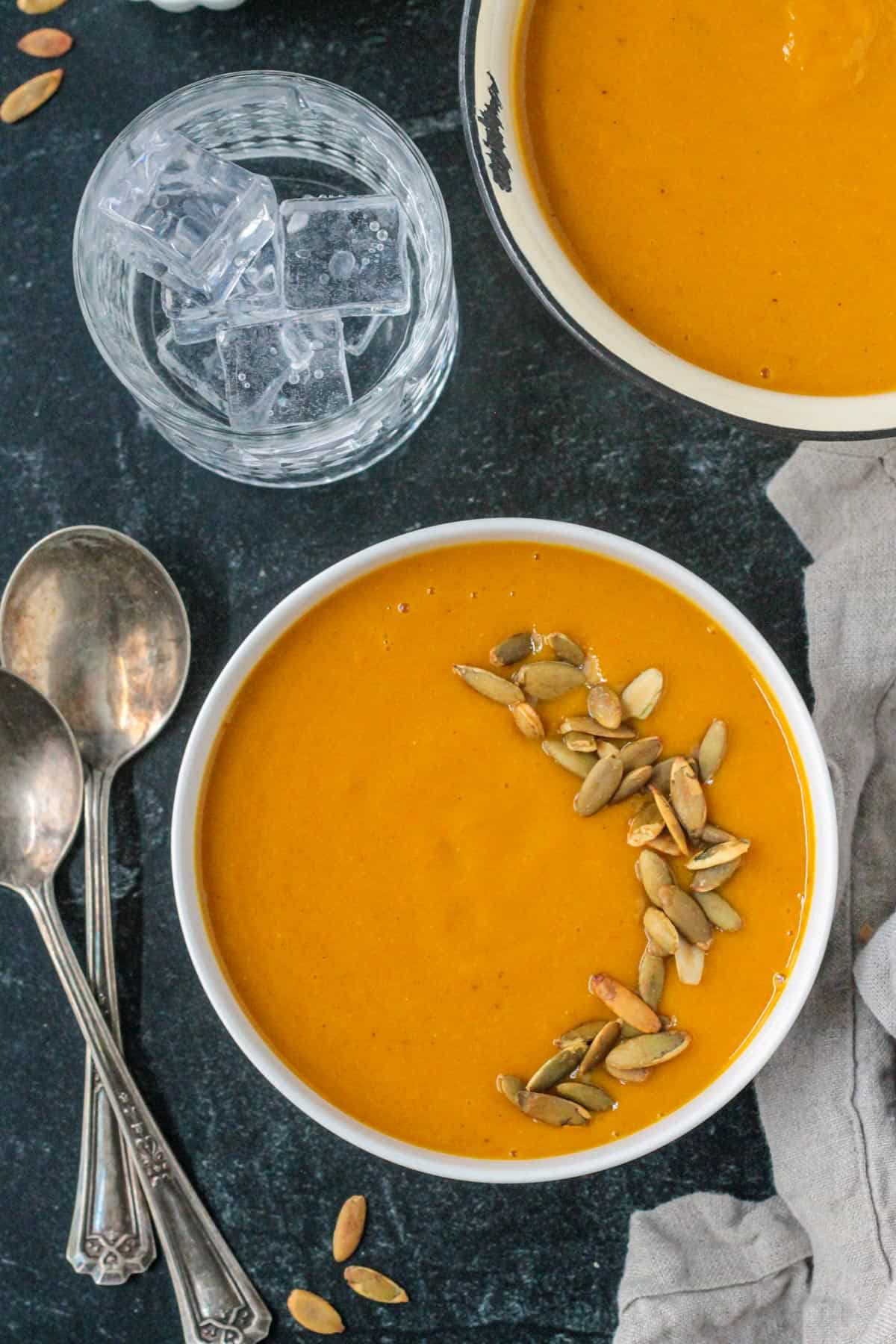 Bowl of butternut squash soup garnished with roasted pumpkin seeds.