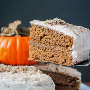 Slice of pumpkin layer cake being lifted from a whole cake.