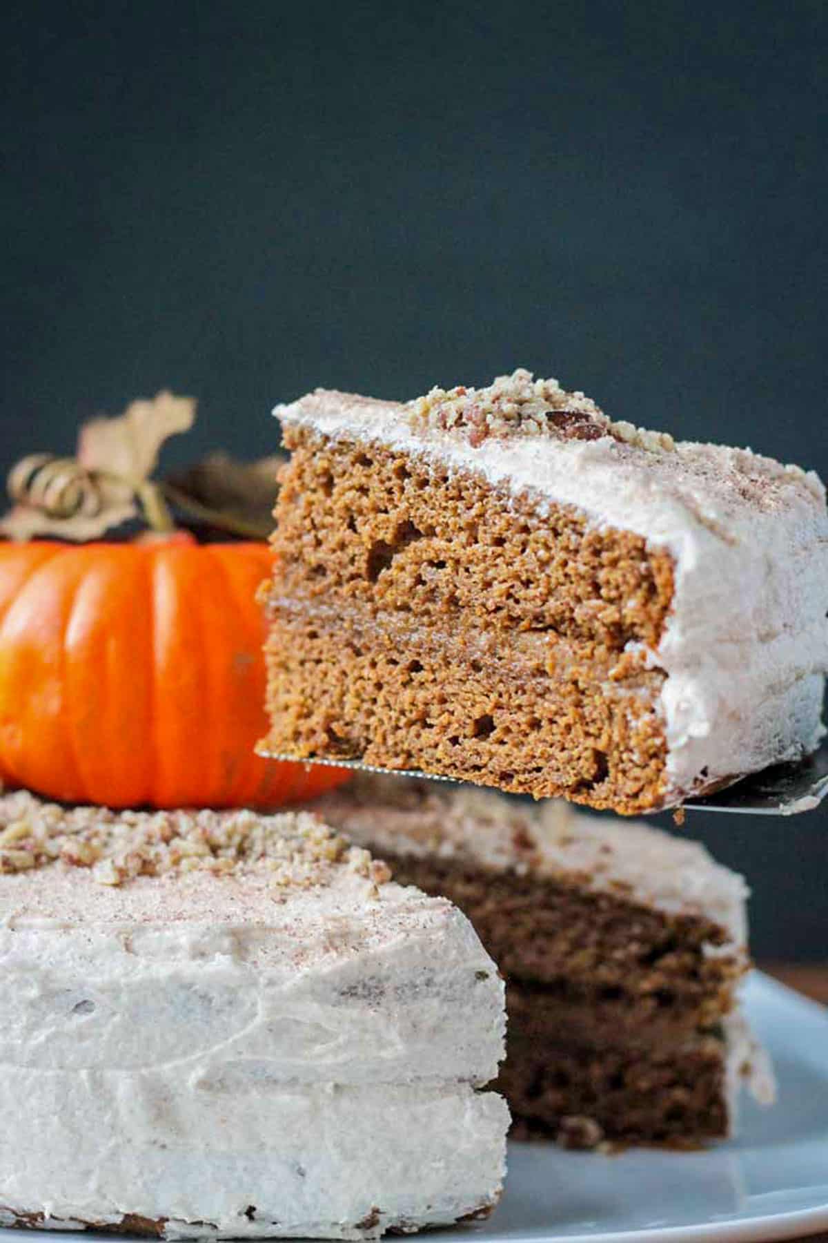 Slice of pumpkin layer cake being lifted from a whole cake.