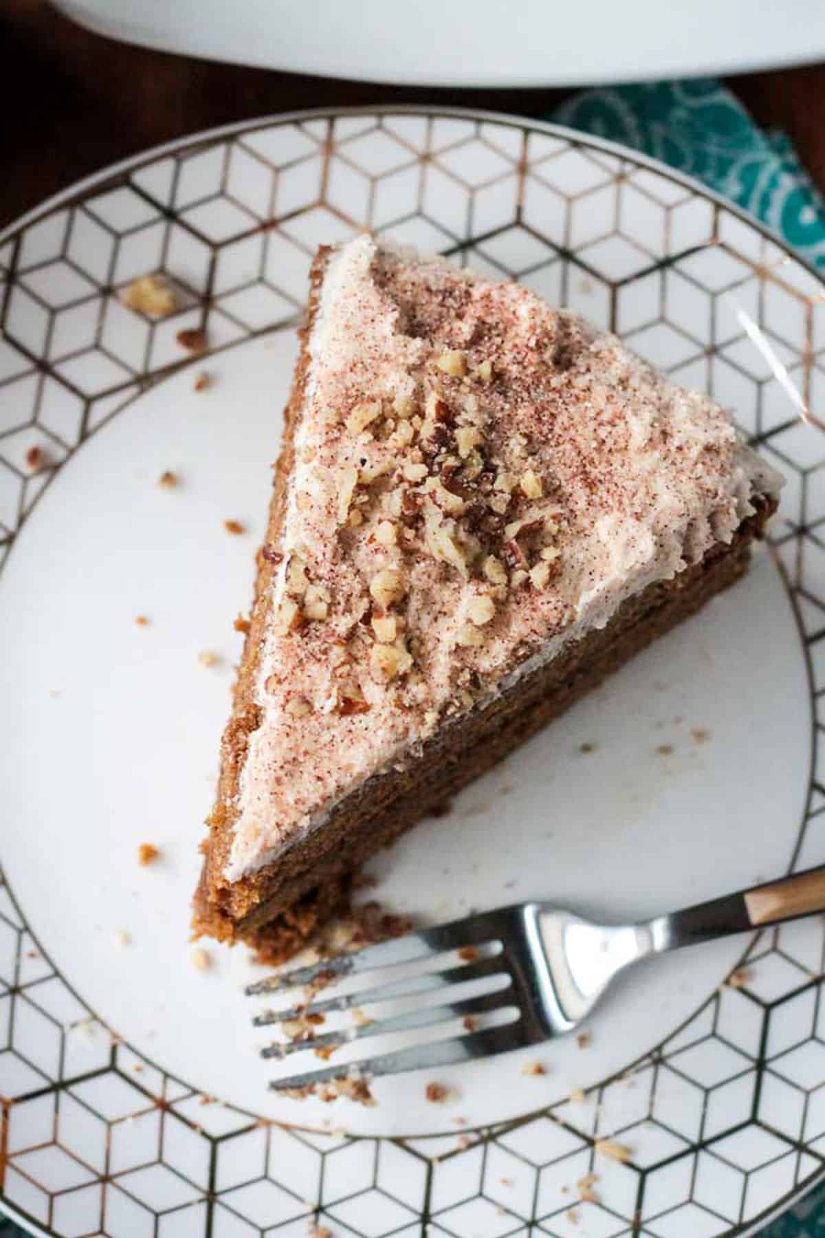 Overhead view of a slice of frosted cake sprinkled with chopped nuts.