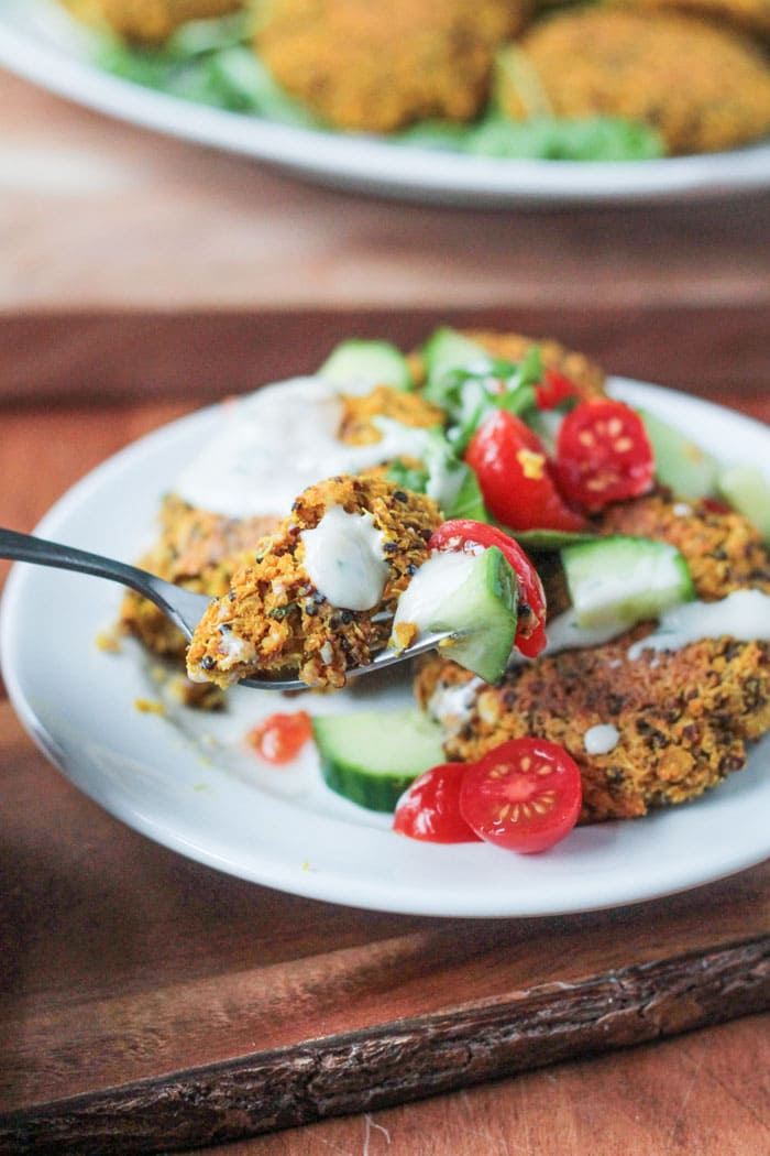 A bite of Baked Red Lentil Quinoa Fritters on a fork with cucumber and tomato. 