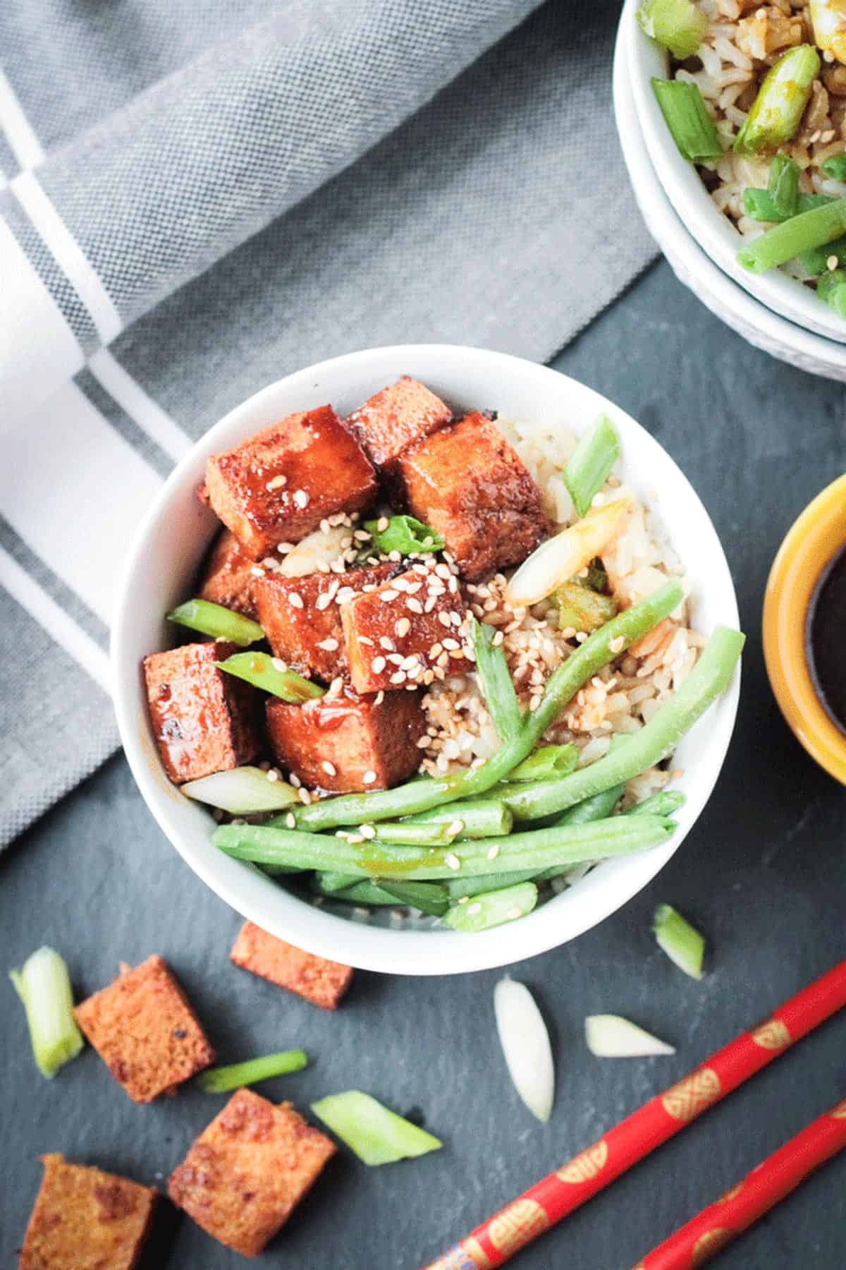 Sesame ginger spiced cubes of baked tofu in a bowl with green beans and rice.