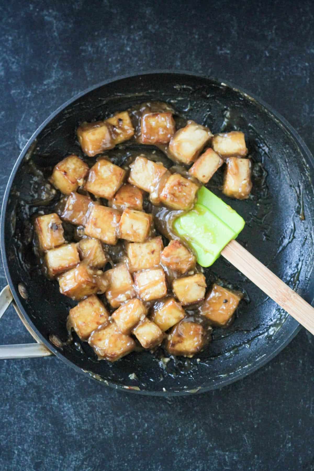 Tofu cubes in a sticky, saucy glaze in a skillet.