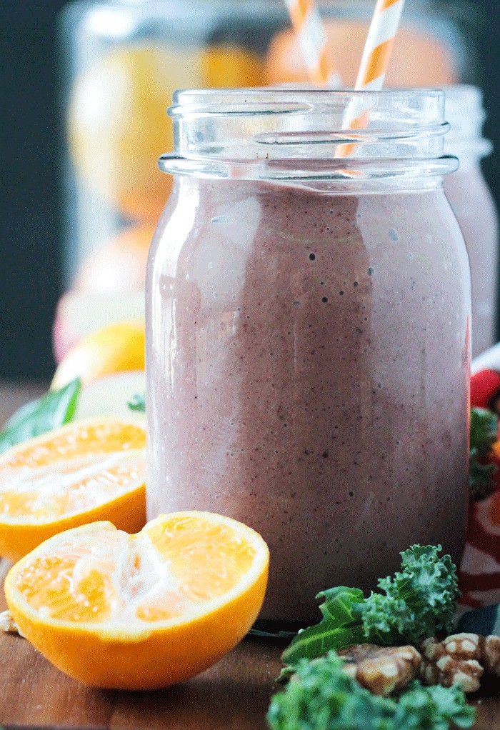 Superfood smoothie in a glass jar with and fresh orange half in front.